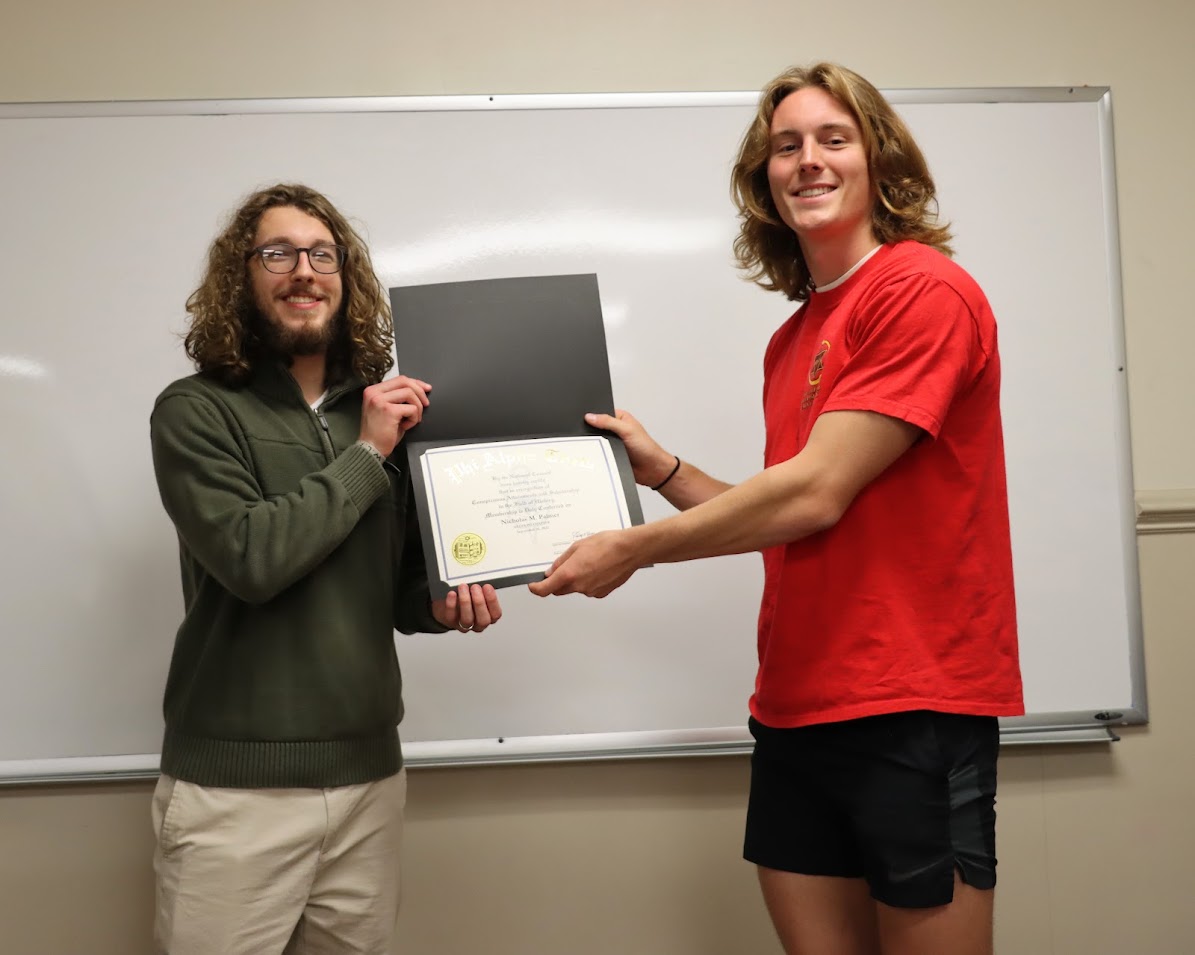 Nicholas Palmer (left) accepts his Phi Alpha Theta membership certificate from Delta-Psi President Tad Binkley on September 26, 2022.