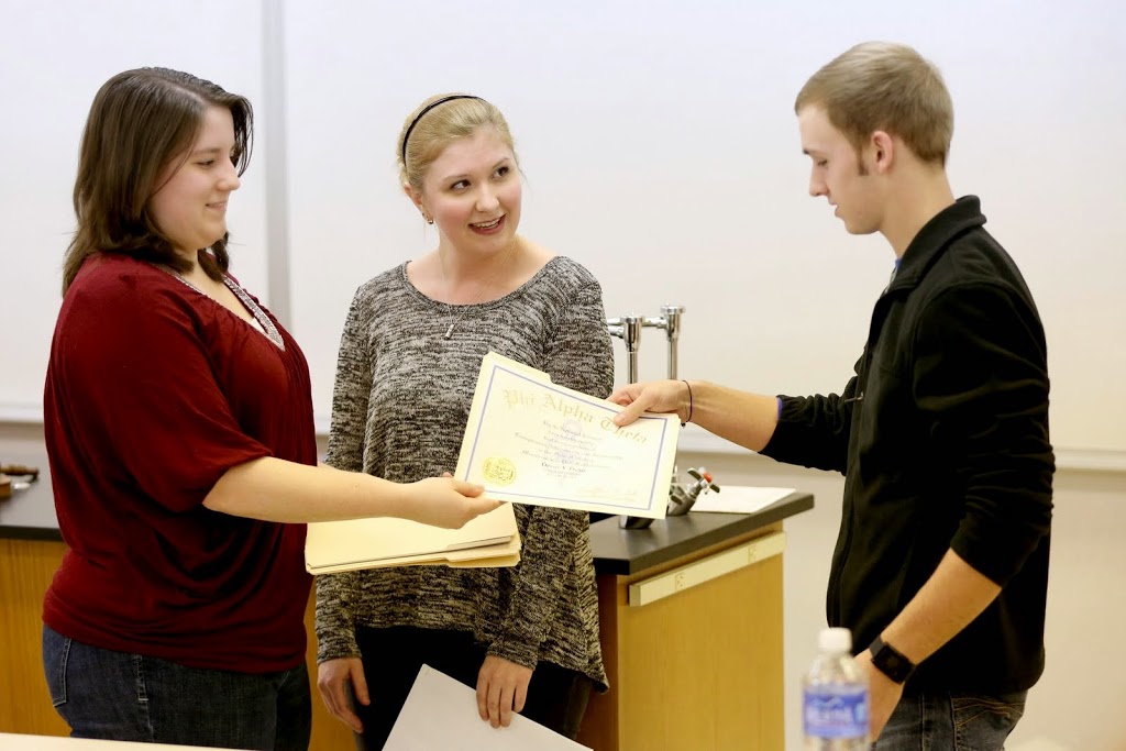 Phi Alpha Theta initiate Devin Dean accepts his certificate of membership from Delta-Psi Chapter President Faith Bagley (left) at the society's spring plenary meeting on February 24, 2015. Vice President (center) watches the ceremony.  Photo by Kristi Woody