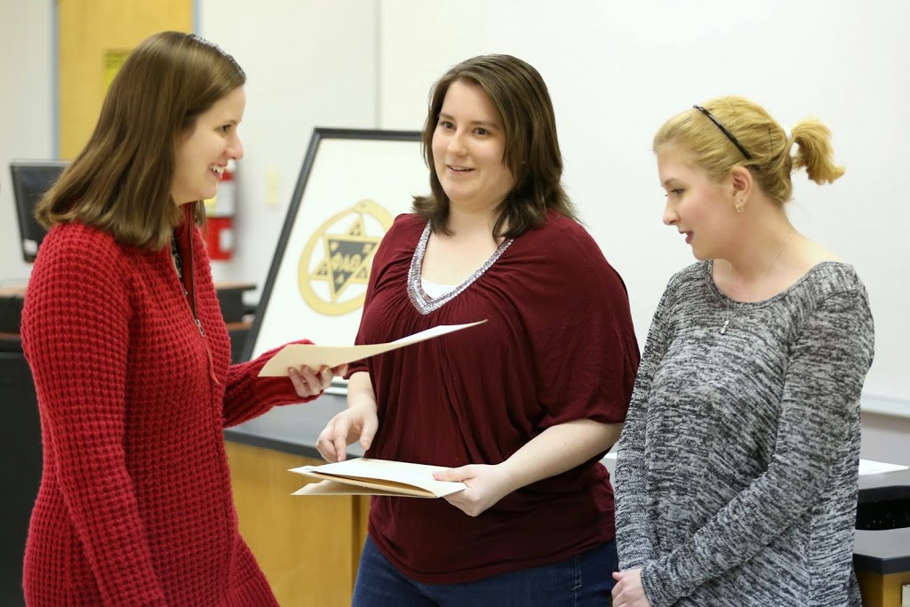Phi Alpha Theta initiate Kayla Ketner (left) smiles as she receives her membership certificate from Delta-Psi President Faith Bagley (center) at the chapter's spring initiation on February 24, 2015. Hannah Jones, the chapter vice president, is on the right.  Photo by Kristi Woody