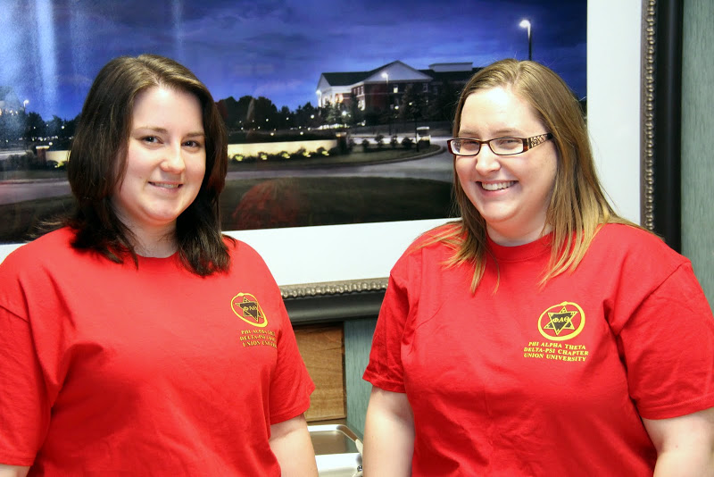 Faith Bagley (left) and Hannah Conway, responsible for taking care of the sales tables for the chapel phase of Phi Alpha Theta's bake sale, wait for that part of the event to begin on March 18, 2015.