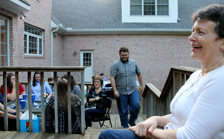 Dr. Alice-Catherine Carls (right) enjoys a light moment during a program honoring graduating seniors at the Phi Alpha Theta cookout on May 13, 2016. History major Nicholas Hancock walks up the deck steps to be recognized for his years at Union University.