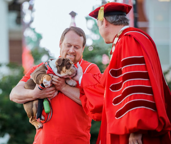 Union University President Samuel W. Dub Oliver (right) greets Buster, Union's English bulldog mascot, during the school's commencement services on May 21, 2016. Holding Buster is Ken Litscher, Union's Director of Residence Life.  Buster was the gift of the class of 2016 to Union University. Photo by Kristi Woody