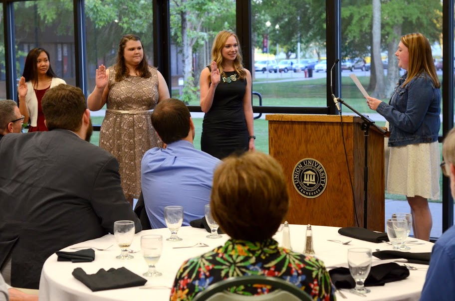 Rutledge Honorary History Club President Kathryn Mitchell (right, standing) conducts the oath of office for new officers Katherine Cheshire (left to right, standing), Jessica Barton, and Ali Renckens at the history awards banquet on May 5, 2016. Photo by MiKalla Cotton