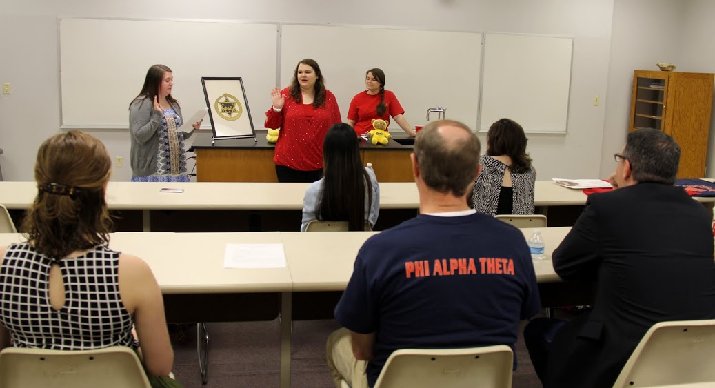 Delta-Psi Vice President Kathryn Mitchell (standing, front left) initiates Jessica Barton into Phi Alpha Theta at the society's plenary meeting on February 20, 2017.