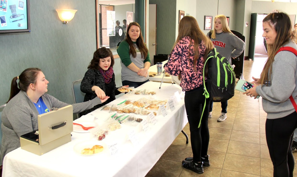 Phi Alpha Theta members Kathryn Mitchell (left to right), Priscilla Porter, and Jordan Sellers sell baked goods to students after chapel at the Franco-American Confection and Bake Sale on March 22, 2017.