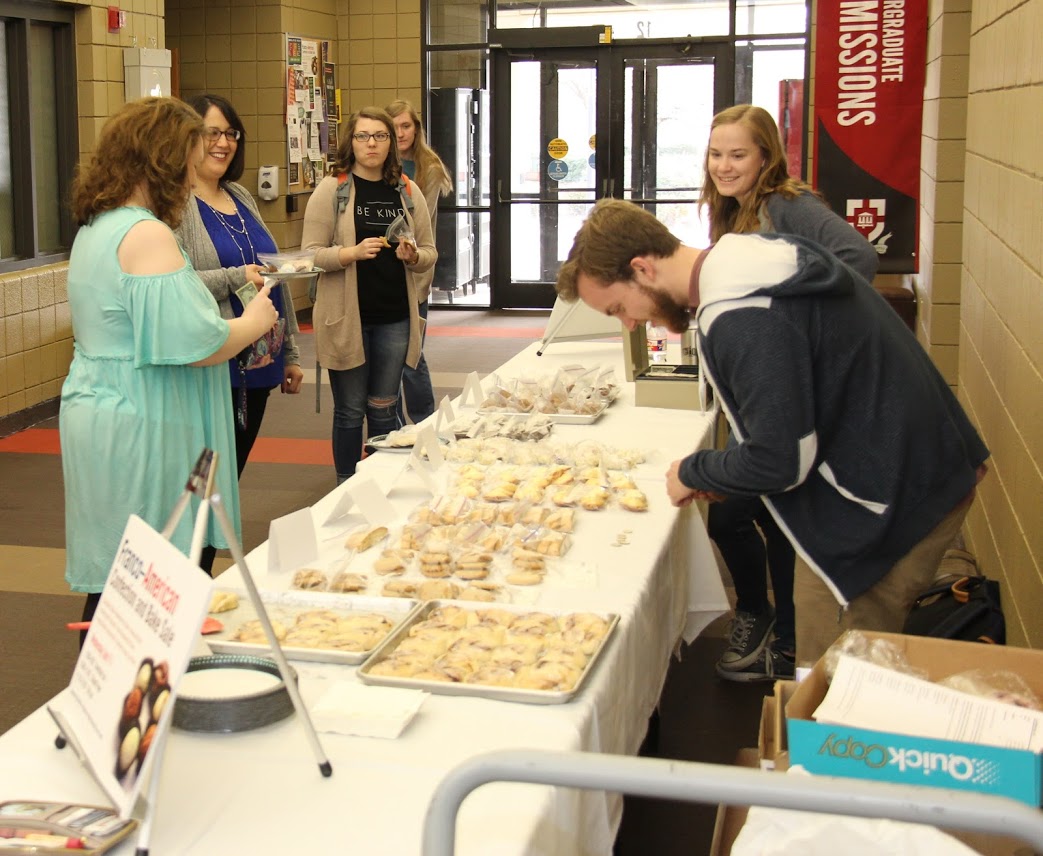 Seth Reid (right front) waits on a customer near Barefoots Joe during the 15th Annual Phi Alpha Theta Franco-American Confection and Bake Sale on April 11, 2018. Fellow Phi Alpha Theta member Megan Ledbetter (to Reid's right) observes.