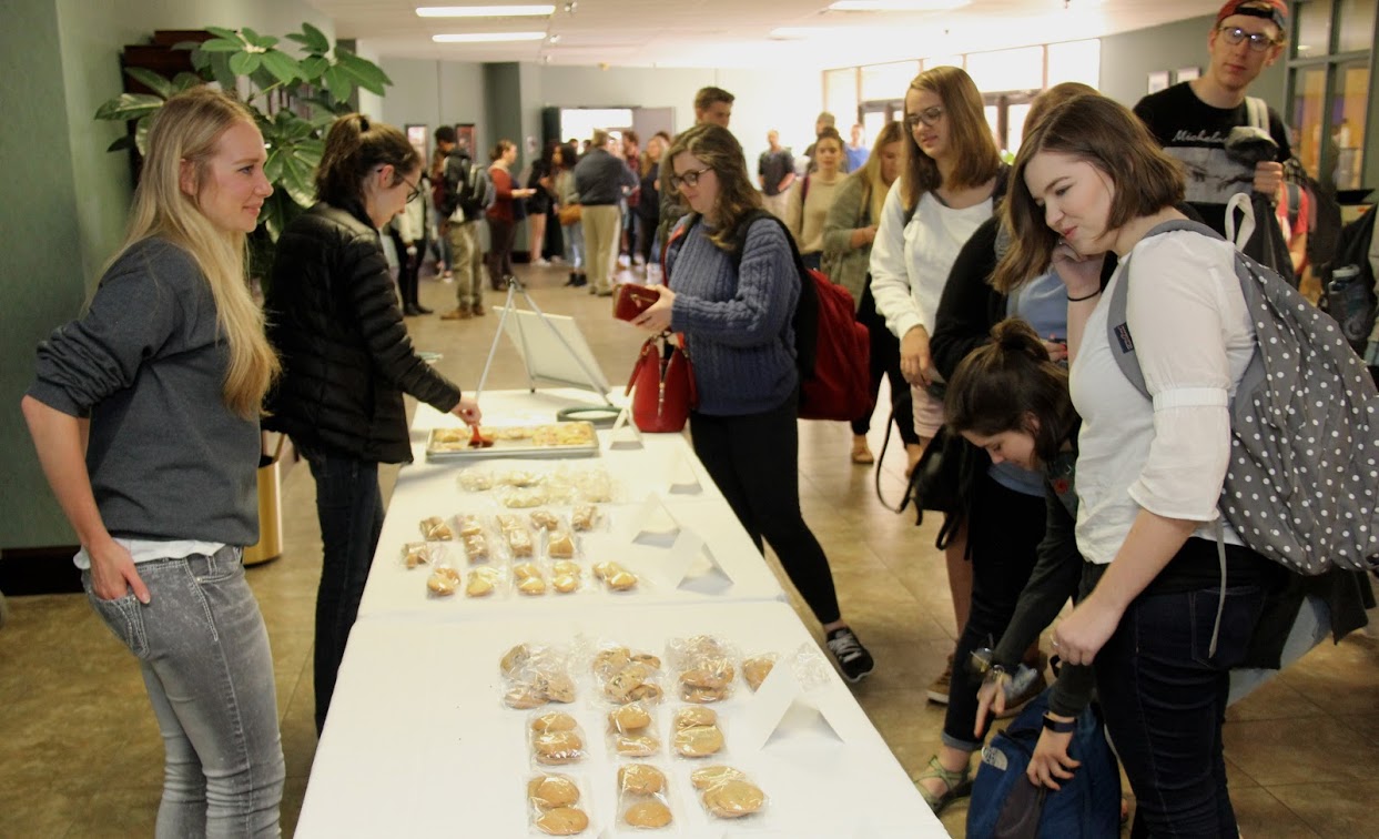 Ali Renckens (front left) and Lauren Butler (to Renckens' left) wait on students in the chapel foyer at the annual Phi Alpha Theta bake sale on April 11, 2018.