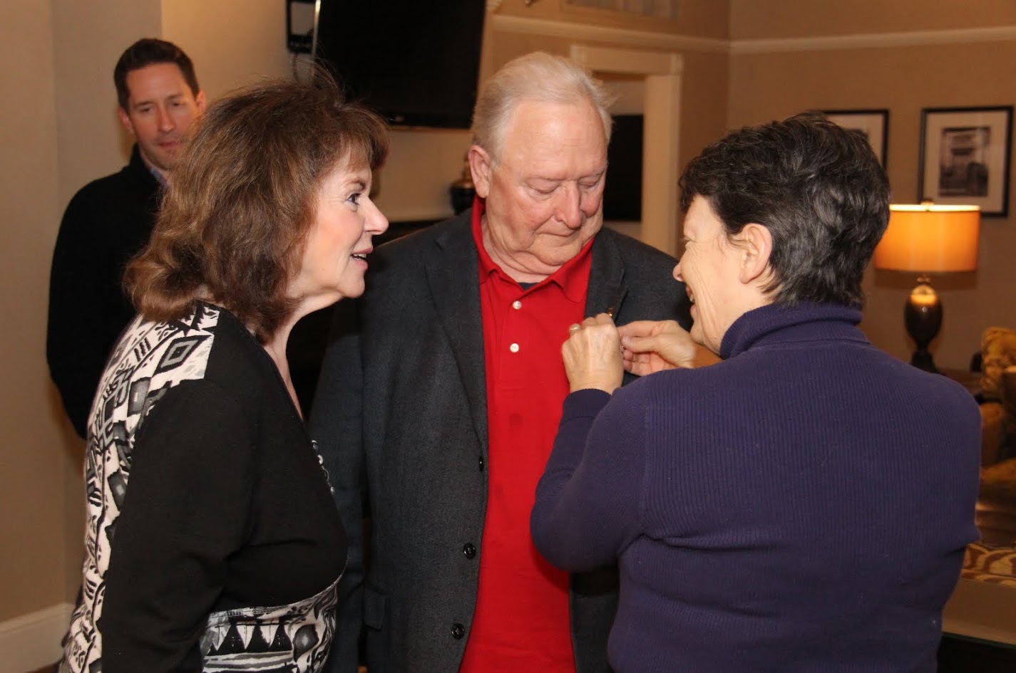 Dr. Alice-Catherine Carls (right) places a Tennessee Great War Commission pin on the coat lapel of Phi Alpha Theta Executive Director Graydon Tunstall in a special ceremony on January 5, 2018, while Dr. Tunstall's wife Wendy (left) looks on.
