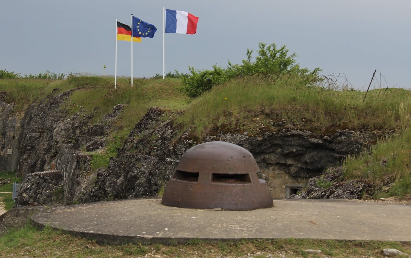 An armored observation cupola sits on Fort Douaumont, with the (left to right) German, European Union, and French flags flying in the background. The World War I travel group from West Tennessee toured the fort on May 27, 2018.