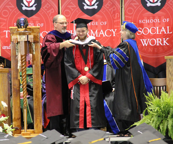 History major Seth Reid (center) receives his hood at Union's spring graduation on May 19, 2018, for successfully completing the Discipline-Specific Honors Program in History. Drs. Scott Huelin and Jill Webb place the hood over his graduation robe.
