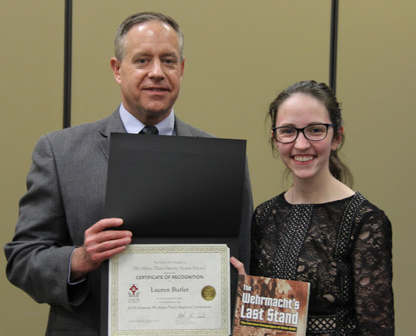 Dr. Henry Allen presents a recognition certificate and a book to Lauren Butler at the history awards banquet on May 3, 2018, for the paper she presented at the Arkansas Phi Alpha Theta Regional Conference on April 7, 2018. Photo by Katherine Cheshire