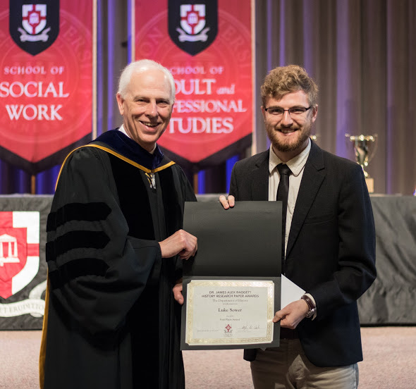 Phi Alpha Theta member Luke Sower (right) accepts the first place award from Dr. Stephen Carls in the Dr. James Alex Baggett History Research Paper Competition during Union University's Awards Day Convocation on May 4, 2018. Photo by Janelle Vest