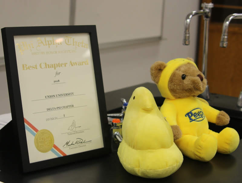 The Delta-Psi chapter's 2018 Phi Alpha Theta Best Chapter Award and two stuffed Peeps animals decorate the workstation countertop in the classroom where the chapter held its plenary meeting on February 26, 2019. Photo by Sarah Goff