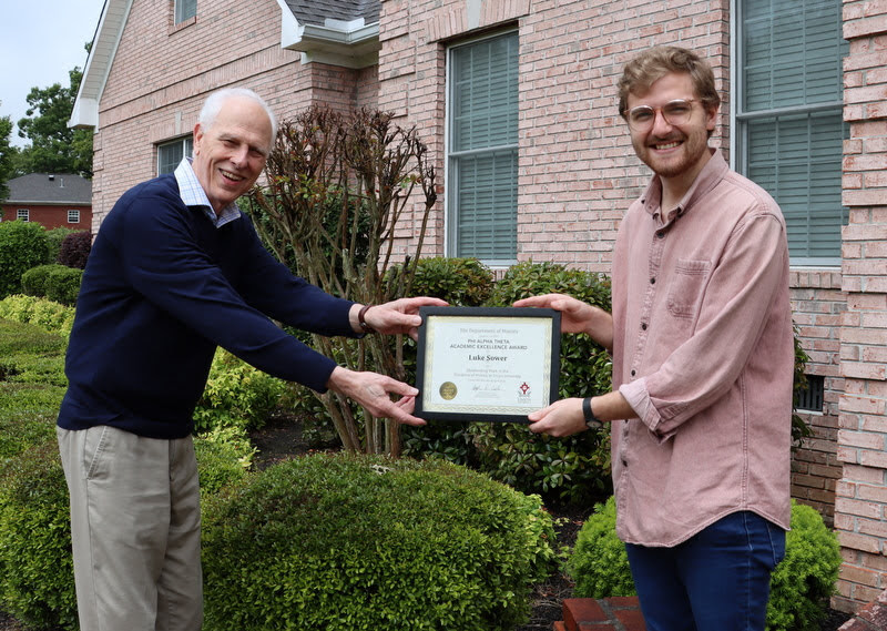 Graduating history major Luke Sower (right) accepts the Phi Alpha Theta Academic Excellence Award from Dr. Stephen Carls in May 2020. The award also consisted of a Phi Alpha Theta Scholarship Pin.