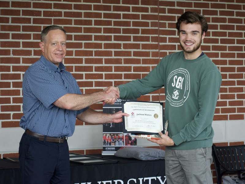 Dr. Henry Allen (left) gives a certificate of commendation and a book to Jack Waters on April 29, 2021, for his paper presentation at the Phi Alpha Theta Super-Regional Virtual Conference at the University of Arkansas on March 13. Photo by Naomi Mengel