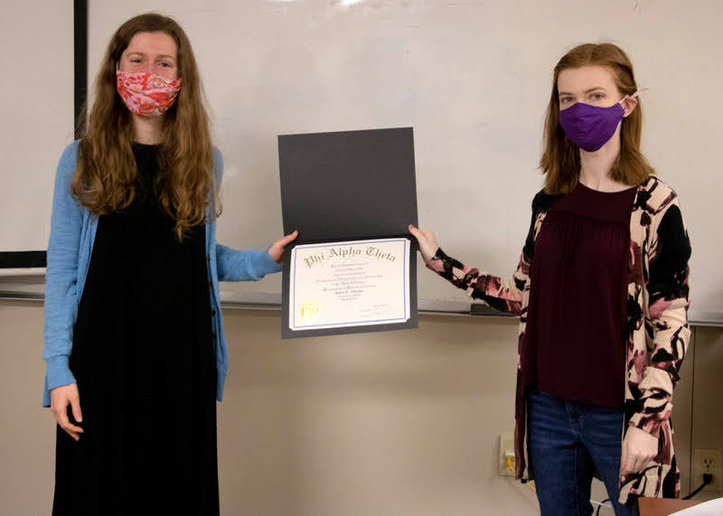 Anne Adams (left) accepts her Phi Alpha Theta membership certificate from Delta-Psi Chapter President Savannah Wright at the society's plenary meeting on March 10, 2021. Photo by Joey Echeverria