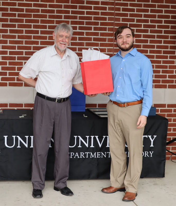 Dr. Terry Lindley (left) presents a graduation gift award to graduating history major Walker Beasley at the History Department Awards Program on April 28, 2022.