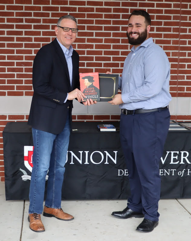 Dr. Keith Bates (left) presents a book and certificate of recognition to Nicholas Terra at the History Department Awards Program on April 28, 2022, for the excellent paper Terra presented at the Arkansas Phi Alpha Theta Regional Conference on April 2, 2022.