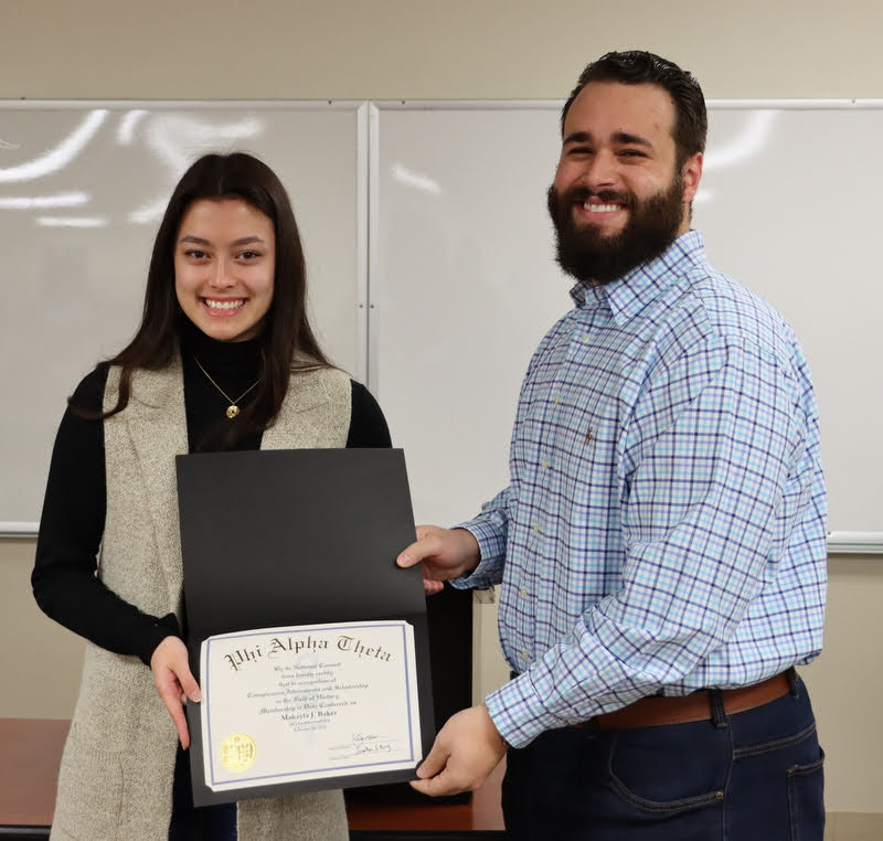 Delta-Psi President Nick Terra presents Makayla Baker with her Phi Alpha Theta certificate of membership at the chapter's spring initiation/plenary meeting on February 28, 2022. Photo by Stephen Carls
