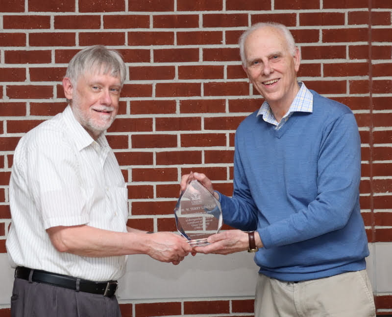 Dr. Stephen Carls (right) presents a crystal retirement award to Dr. Terry Lindley at the History Department Awards Program on April 28, 2022.