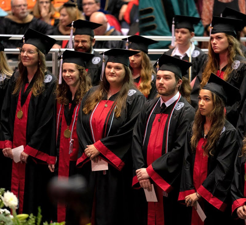 Graduating history majors are among those standing during the academic processional at the undergraduate commencement on May 21, 2022. They are (starting with the second student on the left and moving right across the front row) Anne Adams, Sandra Allen, and Walker Beasley. Photo by Kristi Woody
