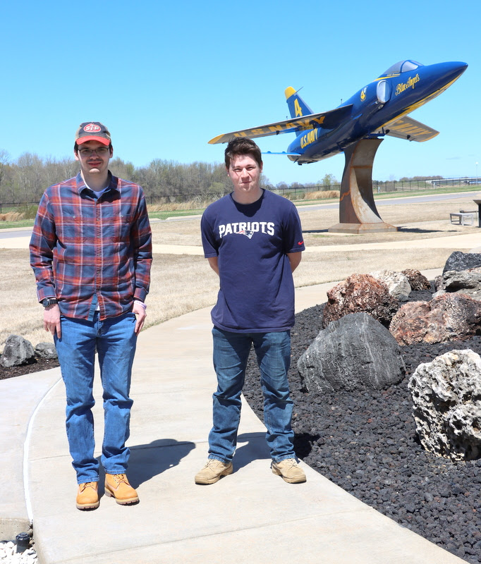 William Houston (left) and Noah Kea stand in front of a Blue Angels jet plane (a Grumman F-11 Tiger) at Discovery Park of America on April 1, 2023.