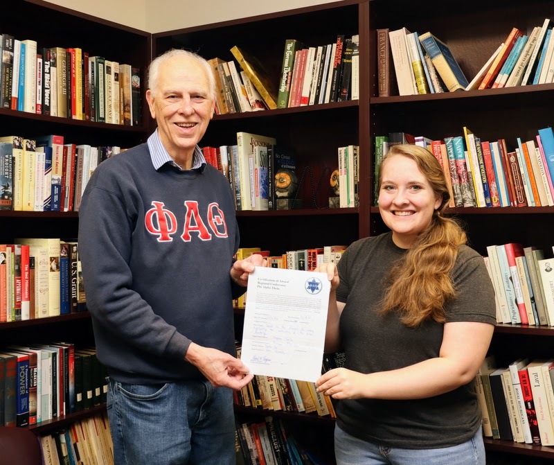 Breanna Edmiston accepts her runner-up award in the undergraduate best paper competition at the 2023 Kentucky Phi Alpha Theta Regional Conference from Dr. Stephen Carls on May 2, 2023.