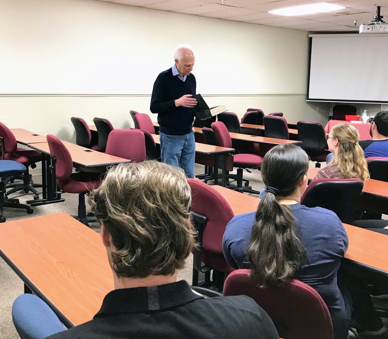 Dr. Stephen Carls opens a book-shaped box containing cards of well wishes from attendees at his surprise retirement party on April 24, 2023.