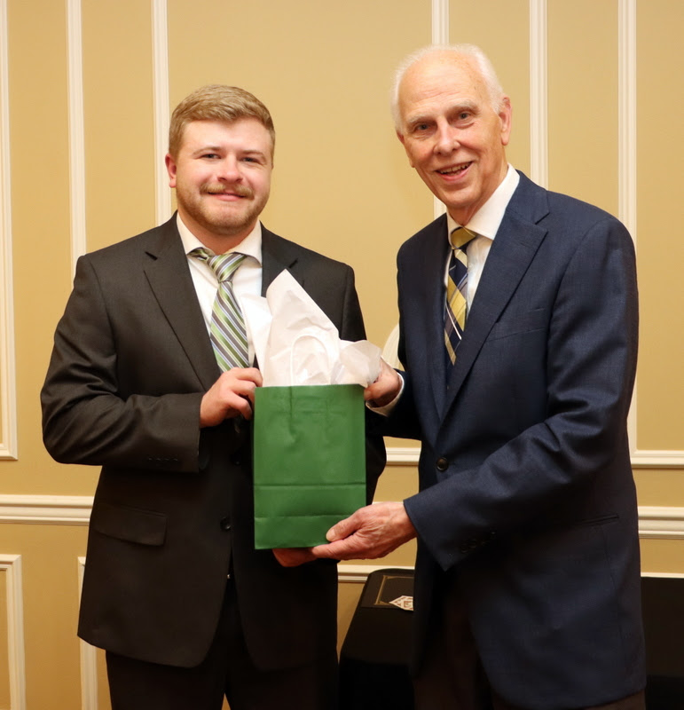 Graduating Phi Alpha Theta member John Garland receives a graduation gift award bag from Dr. Stephen Carls at the History Department Awards Banquet on April 27, 2023.