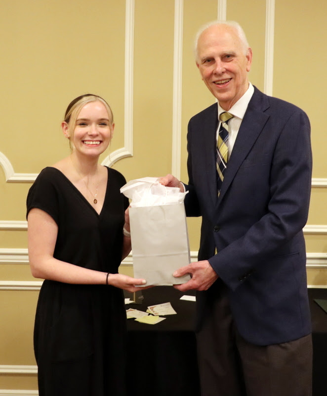 Graduating history major and Phi Alpha Theta member Abbie Hobson accepts a  graduation gift award bag from Dr. Stephen Carls at the History Department Awards Banquet on April 27, 2023.