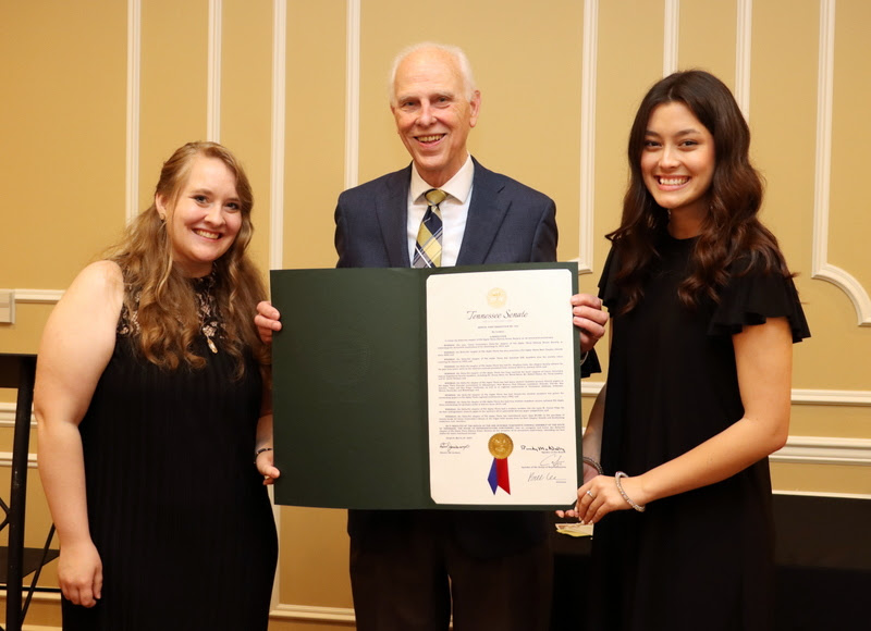 Dr. Stephen Carls stands with Phi Alpha Theta Vice President Breanna Edmiston (left) and President-elect Makayla Baker in announcing at the History Department Awards Banquet the reception of a Tennessee State Senate Resolution passed on March 30, 2023, congratulating the chapter on its 70th anniversary in 2023.