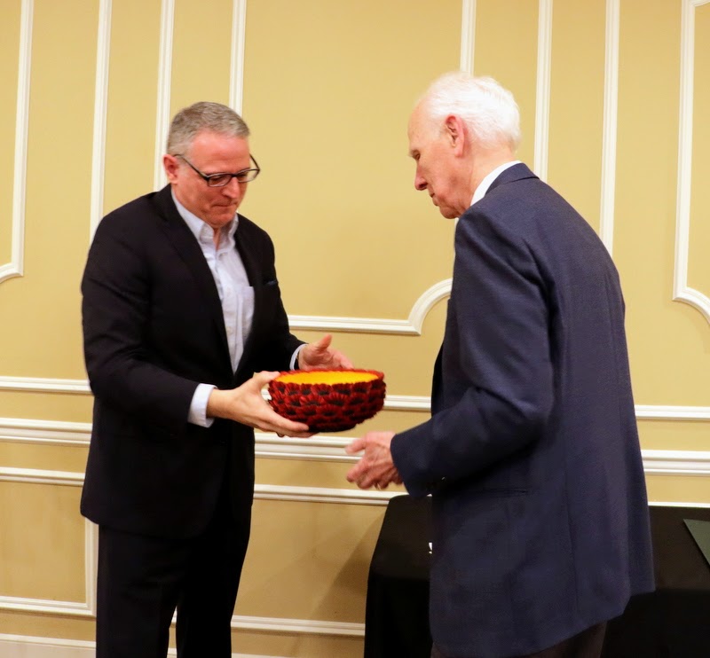 Dr. Keith Bates presents a wood-carved poppies bowl to Dr. Stephen Carls as a retirement gift from the Department of History for Carls' 40 years of service to the department. Carls' daughter Elizabeth Weber, a profession wood turner, made the bowl for the occasion.