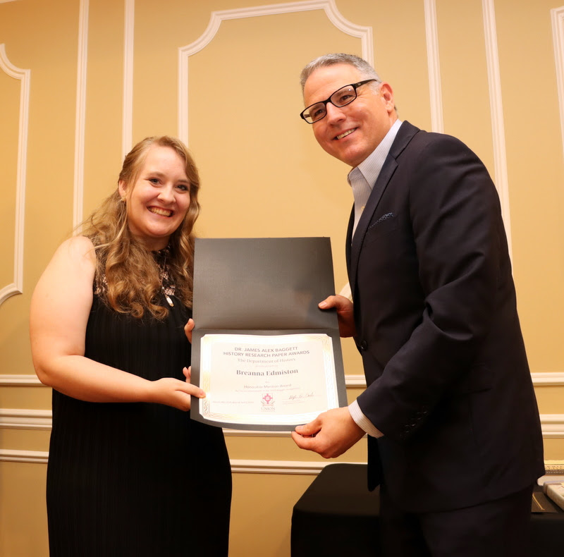 Breanna Edmiston accepts an honorable mention certificate in the Dr. James Alex Baggett History Research Paper Competition from Dr. Keith Bates at the History Department Awards Banquet on April 27, 2023.