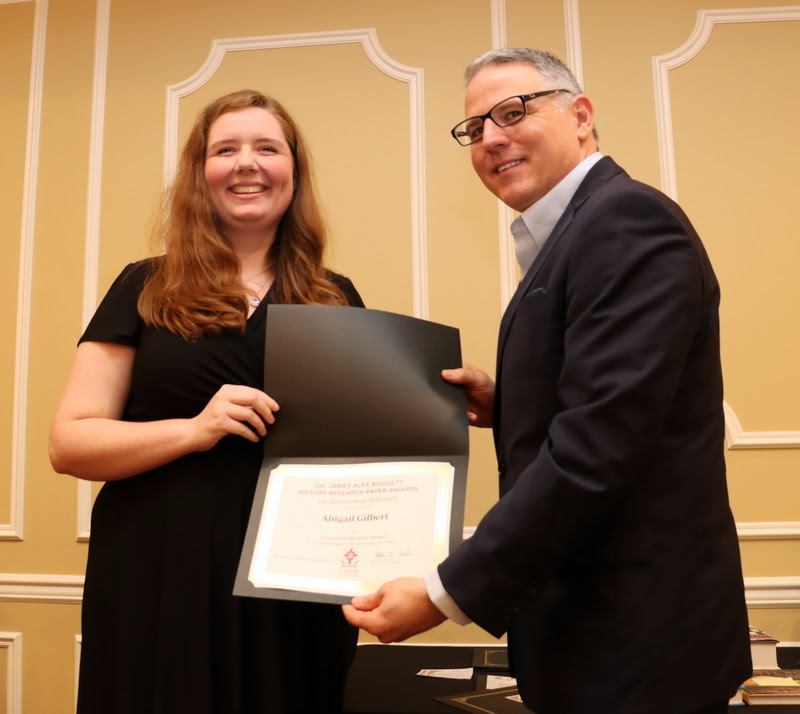 Abigail Gilbert accepts an honorable mention certificate in the Dr. James Alex Baggett History Research Paper Competition from Dr. Keith Bates at the History Department Awards Banquet on April 27, 2023.