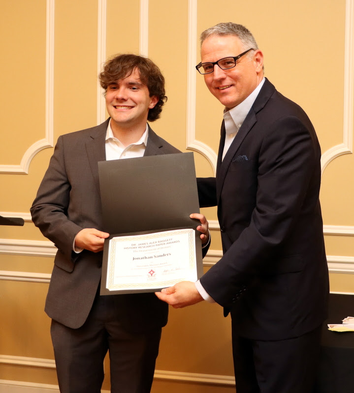 Jonathan Sanders (left) receives an honorable mention certificate in the Dr. James Alex Baggett History Research Paper Competition from Dr. Keith Bates at the History Department Awards Banquet on April 27, 2023.