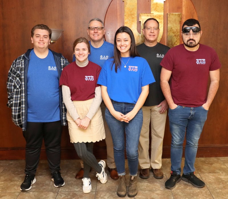 Some of the 2023-2024 Delta-Psi chapter officers stand with history department faculty members during the Phi Alpha Theta T-shirt Spirit Day on March 20, 2023. The officers (front row) are Austin Alexander, Anna Yadkowski, Makayla Baker, and Christian Young. The two faculty members (back row) are Dr. Keith Bates and Dr. Henry Allen.
