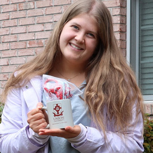 Graduating history major Hannah Ratliff holds her Phi Alpha Theta honor cord and history department coffee mug during a presentation ceremony at Dr. Stephen Carls's home in May 2020.
