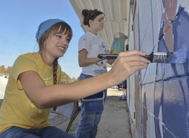 Art students Kristen Witham (left) and Megan Kersey paint a mural on the outside wall of the Freewill Shelter and Outreach in Humboldt, Tenn., as part of Campus and Community: A Day of Remembrance and Service. (Photo by Morris Abernathy)
