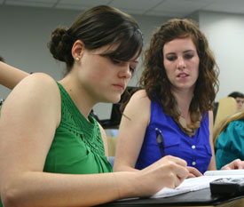 Abby Williams (left) gets help from teammate Kylie McDonald in preparing for the final round in the 2012 International Public Debate Association championship tournament. (Photo by Amelia Krauss)