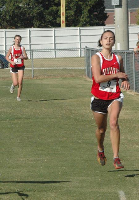 Kayla Hauss checks her time as she crosses the finish line during the Union University Cross Country Invitational. - Photo by Tommy Sadler