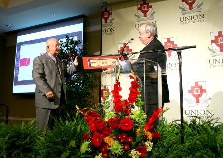 President Dockery presents David Blackstock with a framed print of what the new gym floor will look like.  The floor will be redone in honor of Blackstock, Union's former coach and athletic director. - Photo by Kristi McMurry Woody