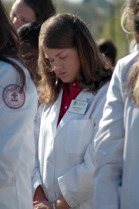 Pharmacy student Megan Rowlett prays during the groundbreaking ceremony of the new academic building for the School of Pharmacy. - Photo by Beth Spain