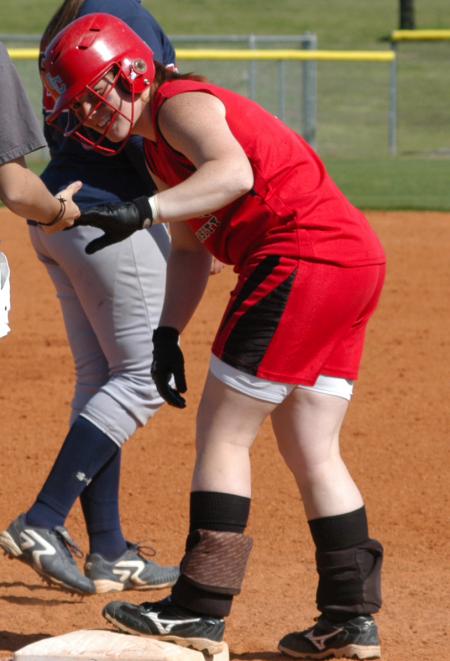 Katie Davis smiles as she stands on first base after a single. - Photo by Steven Aldridge