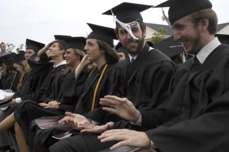Graduate Kieler Henry and Josh Henson have trouble with the wind and their tassels during spring graduation. - Photo by Sarah Palmer Goff