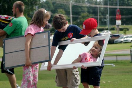 Michael Tankersley (on left), 6, and Daniel Ellsworth, 6, show Zoe Myatt, 7, her reflection as they carry a new student's mirror during move-in day. - Photo by Beth Spain