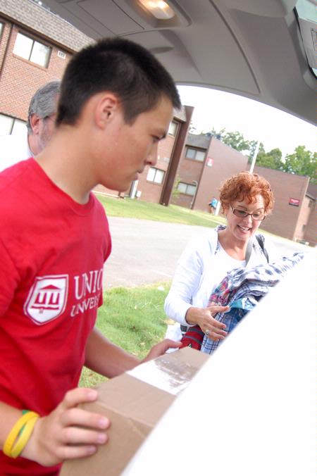 Peter Yu, sophomore, helps Christy Krone, mother of Elsie Krone, move her daughter's belongings to her room on freshman move-in day. - Photo by Kristi McMurry Woody