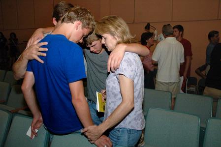 After a long day of moving onto campus, the Hubin family (Carol, mother, Jonathan, brother, Loren, father) prays over their son Josiah at the new student worship service during orientation. - Photo by Beth Spain