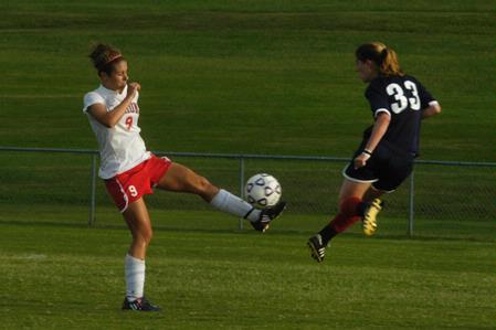 Whitney Kramer kicks the ball while her Lyon College opponent leaps to block the ball. - Photo by Sarah Palmer Goff