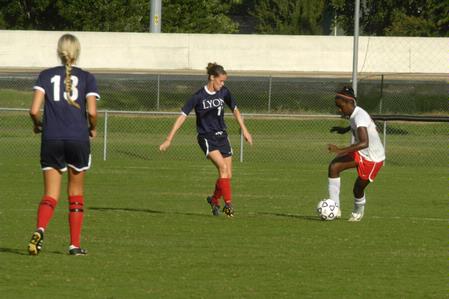 Eboni Murphy, junior, dribbles the ball through her opponents, Lyon College.   - Photo by Sarah Palmer Goff