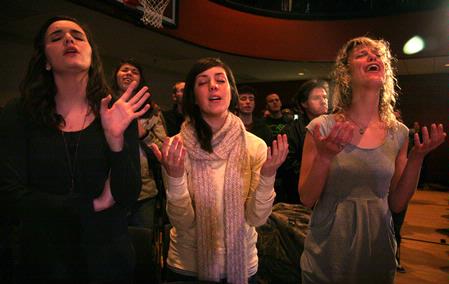 Kari Beogher, junior social work major, Ellen Reinhard, junior public relations major, and Stacy Hanburry, freshman social work major, sing songs of praise at the service commemorating the two-year anniversary of the tornado that hit campus Feb. 5, 2008. - Photo by Angela Abbamonte